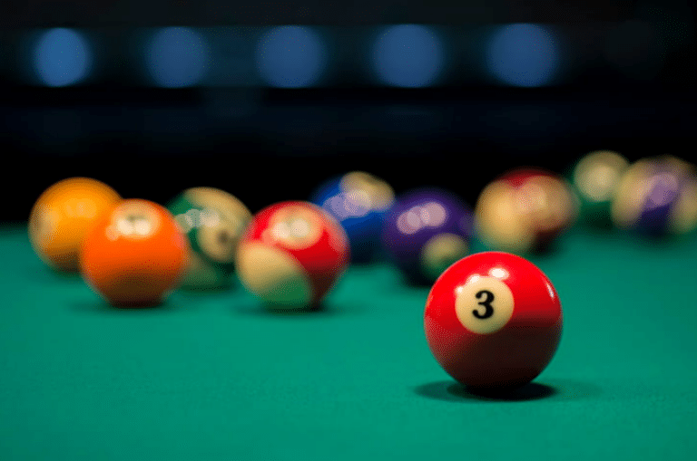 numbered balls on a pool table. Only the number 3 is in focus, the rest are blurred out in the background.