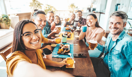 Friends around a table take a selfie while enjoying their meal at a restaurant located near Fremont Street Experience.