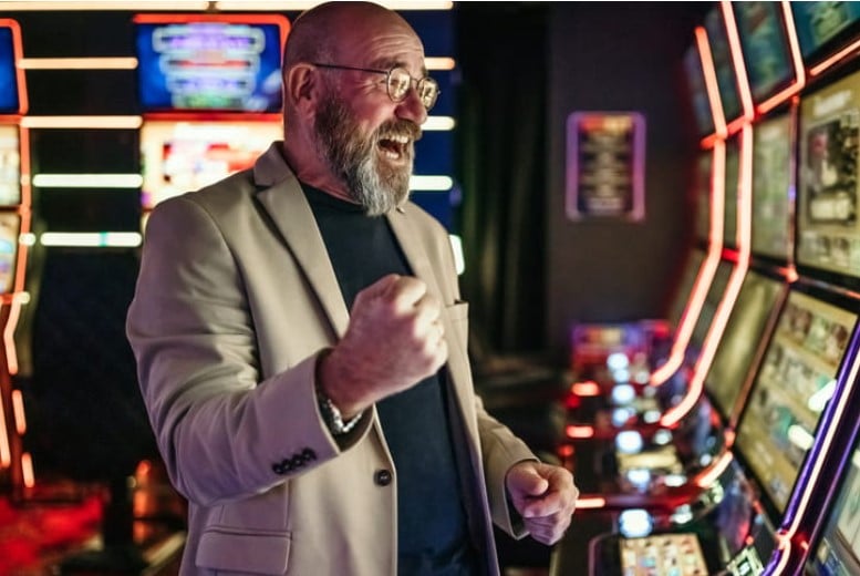 A man cheering at the slot machines after winning.